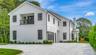 Modern farmhouse with a balcony, a chimney, driveway, and board and batten siding