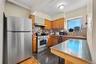 Kitchen featuring appliances with stainless steel finishes, brown cabinets, tasteful backsplash, under cabinet range hood, and granite floors