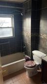 Bathroom featuring vanity, light tile patterned flooring, tile walls, and shower / washtub combination