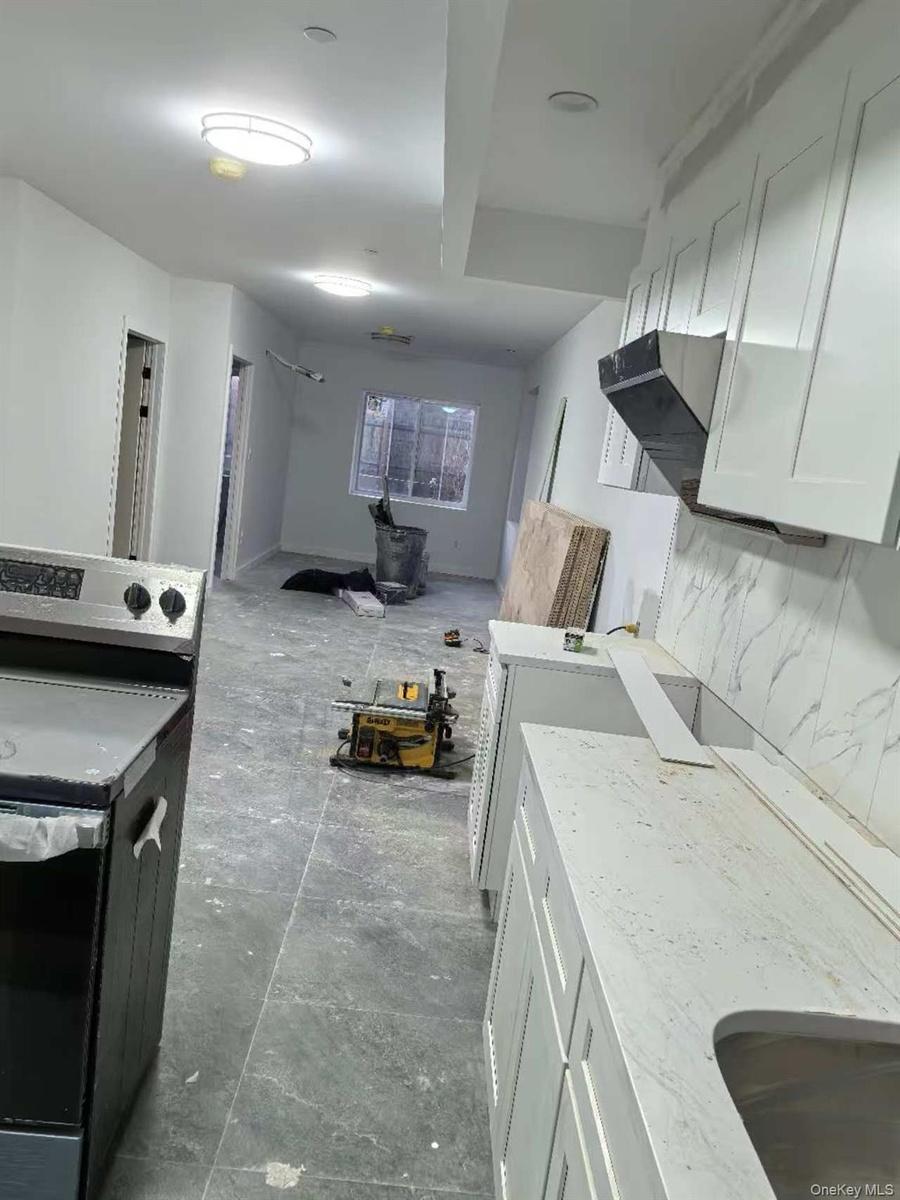 Kitchen featuring light stone counters and white cabinetry
