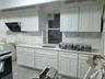 Kitchen featuring white cabinets, decorative backsplash, ventilation hood, and light stone counters