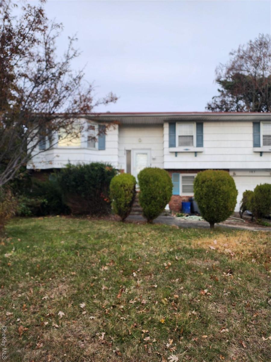 Raised ranch featuring a front yard and brick siding