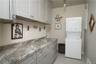 Laundry room with a baseboard radiator, stacked washer / dryer, and cabinets