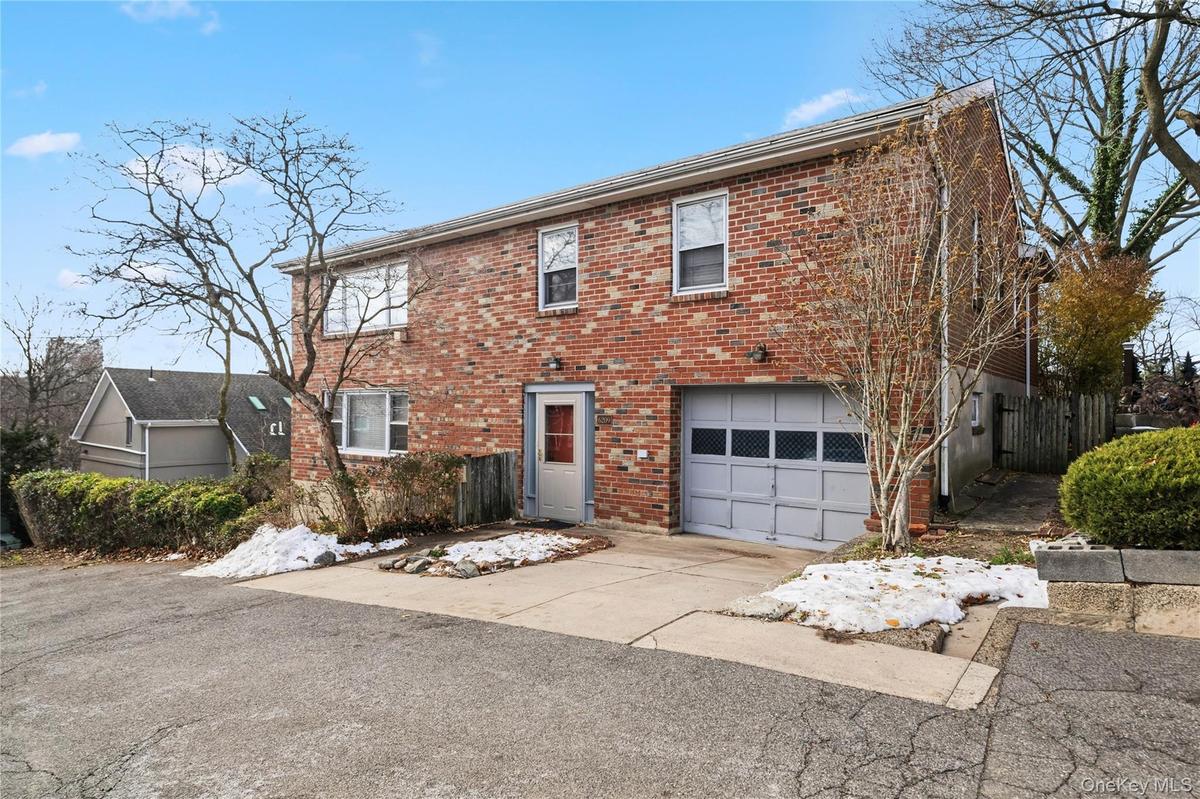 Colonial home featuring brick siding, a garage, and concrete driveway