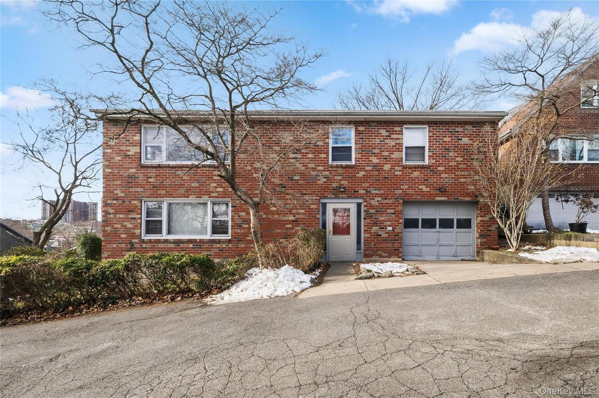 View of front of house with brick siding, an attached garage, and driveway