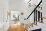 Foyer with light wood-style floors, a towering ceiling, a baseboard radiator, and stairway