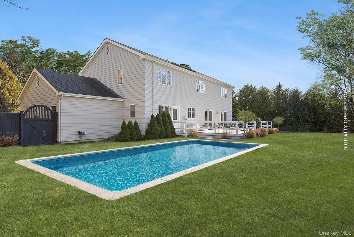 Outdoor pool with a lawn, a wooden deck, and a gate