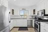 Kitchen featuring appliances with stainless steel finishes, white cabinetry, glass insert cabinets, ornamental molding, and light countertops