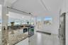 Kitchen with light stone countertops, white cabinetry, hanging light fixtures, appliances with stainless steel finishes, and wood ceiling