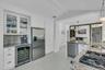 Kitchen featuring light stone counters, white cabinets, pendant lighting, glass insert cabinets, and appliances with stainless steel finishes