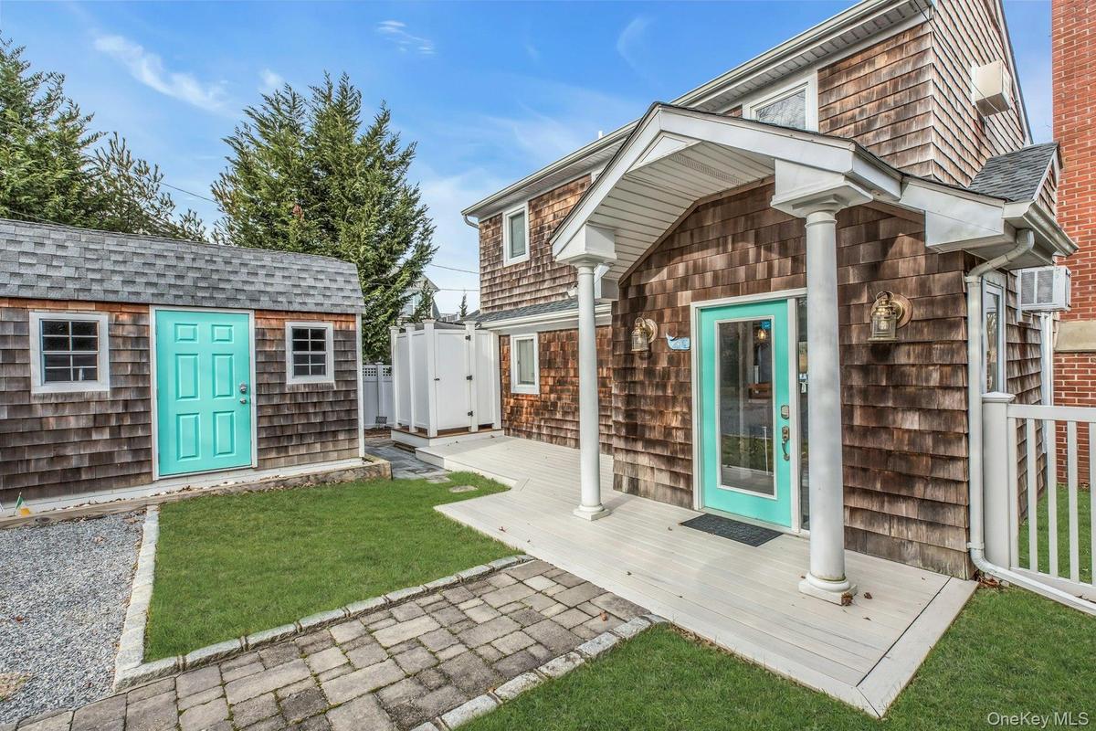 View of exterior entry featuring a deck, a lawn, and roof with shingles