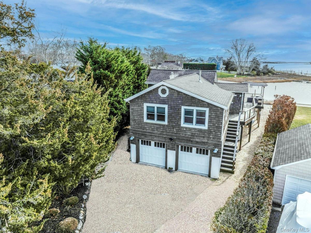 View of property exterior with driveway, stairs, roof with shingles, and a garage