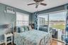 Bedroom with wood finished floors, baseboard heating, ceiling fan, access to exterior, and a wall mounted air conditioner