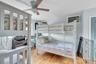 Bedroom featuring wood finished floors, ceiling fan, and a wall mounted AC