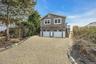 View of property exterior featuring stairway, gravel driveway, and a deck
