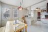 Dining space with a wood stove, ceiling fan, light flooring, and arched walkways