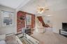 Carpeted living area with a wood stove, brick wall, healthy amount of natural light, a ceiling fan, and baseboard heating