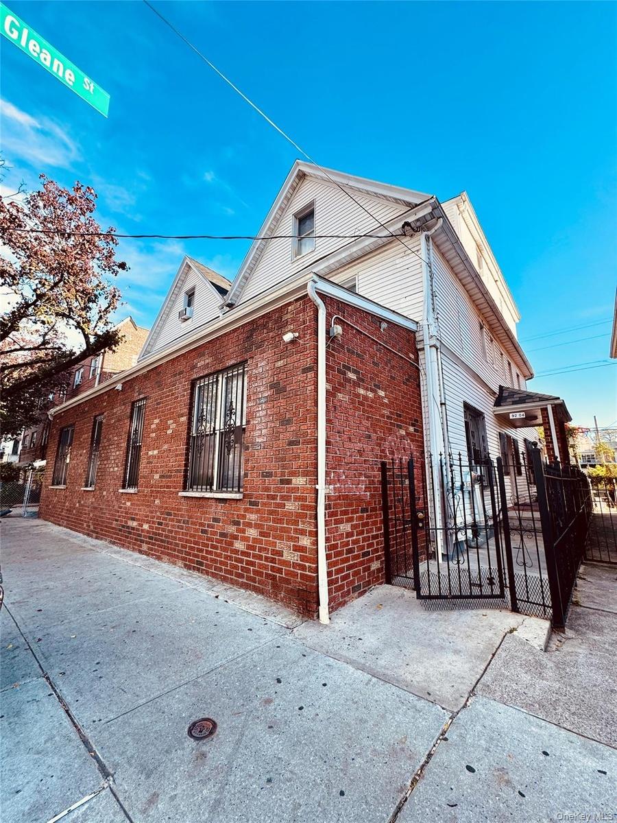 View of side of property with brick siding and a gate