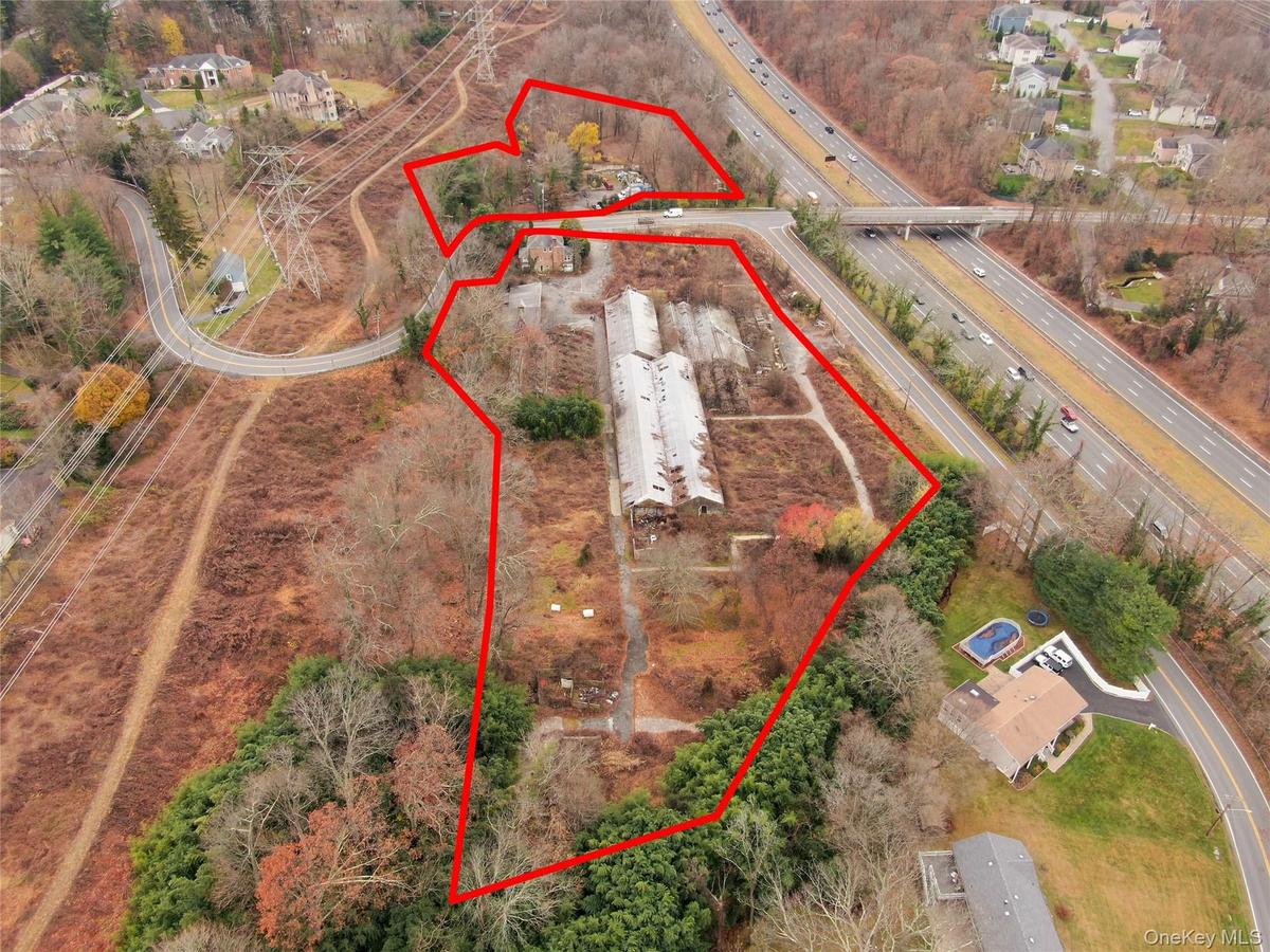 Aerial view of property and surrounding area featuring property boundaries highlighted and a major roadway