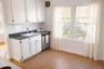 Kitchen featuring white cabinetry, dark countertops, stainless steel dishwasher, and decorative backsplash