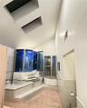 Full bathroom featuring vaulted ceiling, a tub, and a shower with door