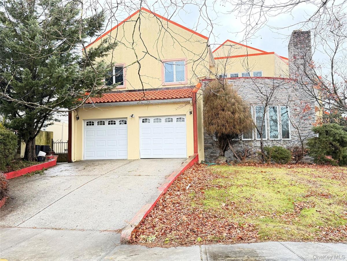 View of front of property featuring a garage, driveway, stucco siding, and a tiled roof