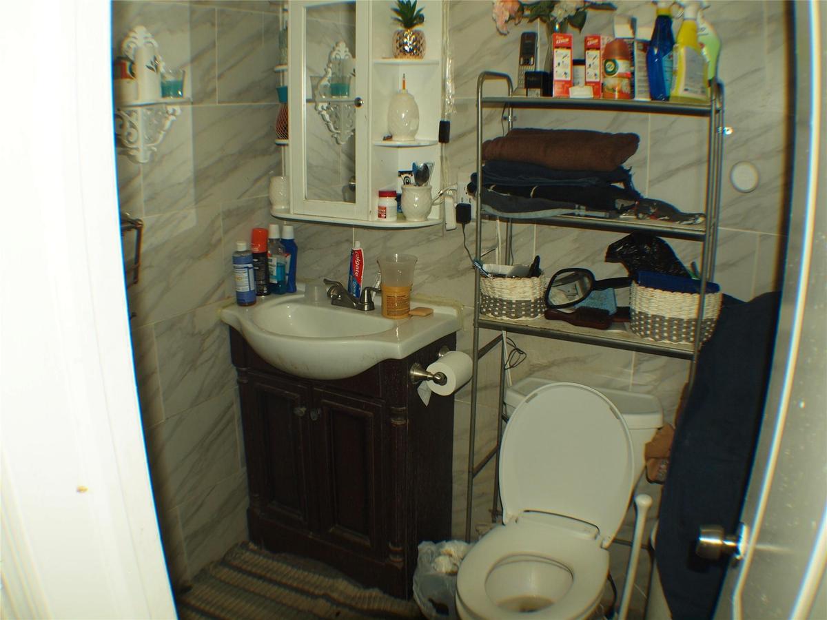 Half bathroom with vanity, tile walls, toilet, and tasteful backsplash