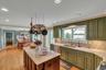 Kitchen featuring green cabinets, crown molding, backsplash, light stone countertops, and a kitchen island