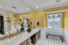 Full bathroom featuring a wainscoted wall, double vanity, crown molding, healthy amount of natural light, and bath / shower combo with glass door