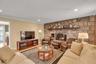 Living area with wood finished floors, a stone fireplace, recessed lighting, and crown molding
