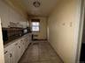 Kitchen with white cabinetry, white gas stove, light stone counters, radiator, and light tile patterned flooring