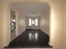 Foyer with arched walkways, radiator, and dark wood-style flooring