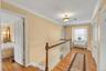 Hall with ornamental molding, light wood-style flooring, and an upstairs landing