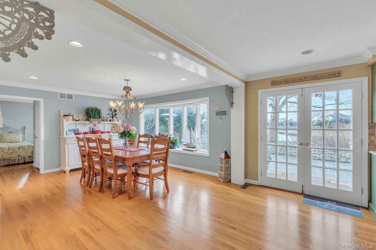 Dining space with light wood-type flooring, crown molding, recessed lighting, french doors, and a chandelier