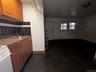 featuring brown cabinetry, white stove, dark countertops, and dark tile patterned flooring