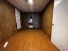 Second bedroom featuring light wood-style floors, a drop ceiling, wooden walls, and radiator heating unit