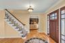 Foyer with light wood finished floors, stairs, ornamental molding, and a fireplace
