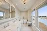 Bathroom with a chandelier, a freestanding tub, wallpapered walls, double vanity, and recessed lighting