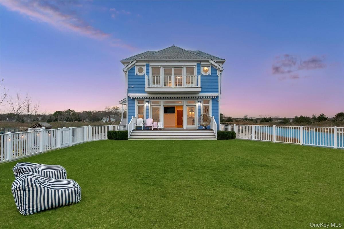 Back of property at dusk featuring a fenced backyard, a balcony, and a patio
