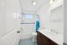 Bathroom featuring shower / tub combo with curtain, vanity, and dark tile patterned flooring
