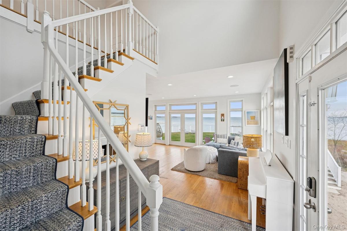 Entrance foyer featuring stairs, a high ceiling, wood finished floors, a water view, and recessed lighting