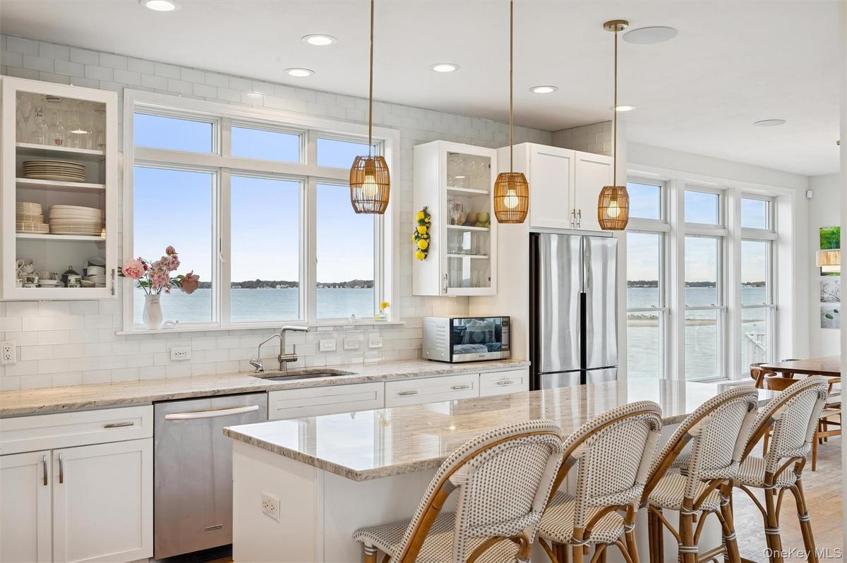Kitchen featuring glass insert cabinets, white cabinetry, a water view, a breakfast bar, and recessed lighting
