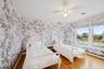 Bedroom with wallpapered walls, wood finished floors, and a ceiling fan