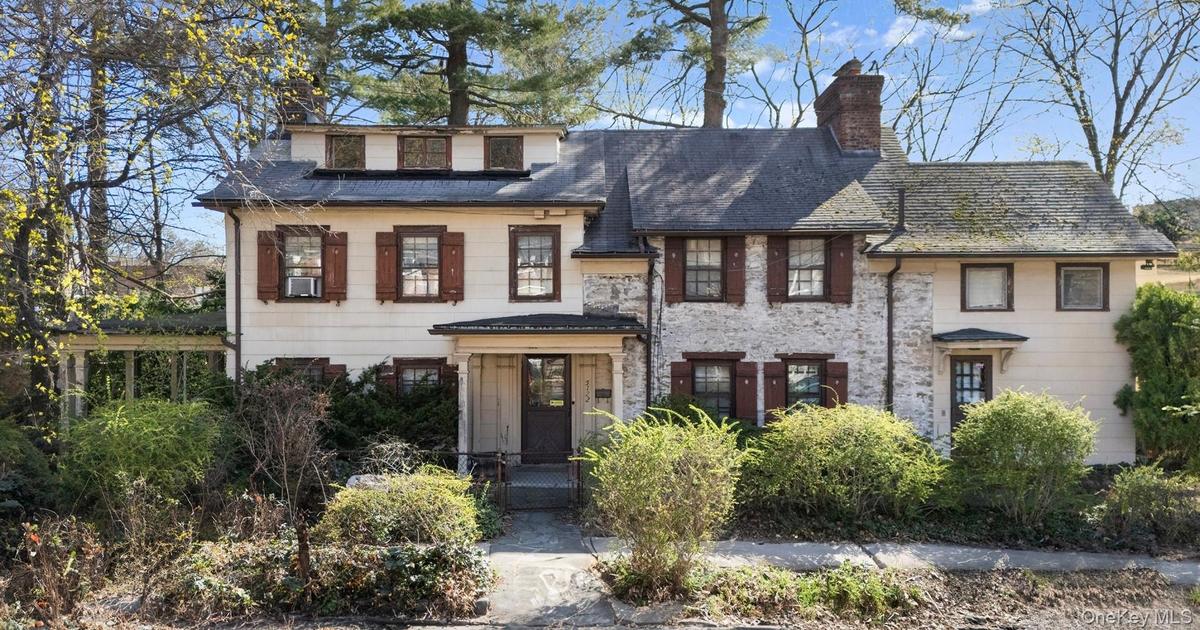 View of front of property with stone siding and a chimney