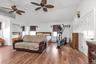 Bedroom featuring vaulted ceiling, a closet, a ceiling fan, wood finished floors, and a wall unit AC