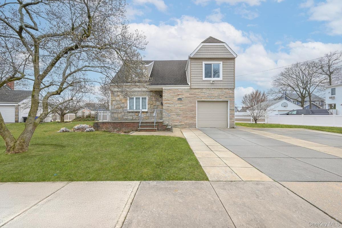 View of front facade featuring stone siding, driveway, an attached garage, and roof with shingles