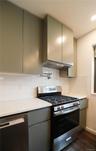 Kitchen featuring appliances with stainless steel finishes, tasteful backsplash, sage green cabinetry, and ventilation hood