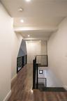 Hall with dark wood-style flooring and recessed lighting. Overlook into the living room space with vaulted ceilings.
