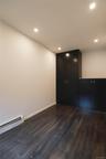 Bedroom featuring a baseboard radiator, dark wood-style floors, and recessed lighting. The room includes two black cabinets.