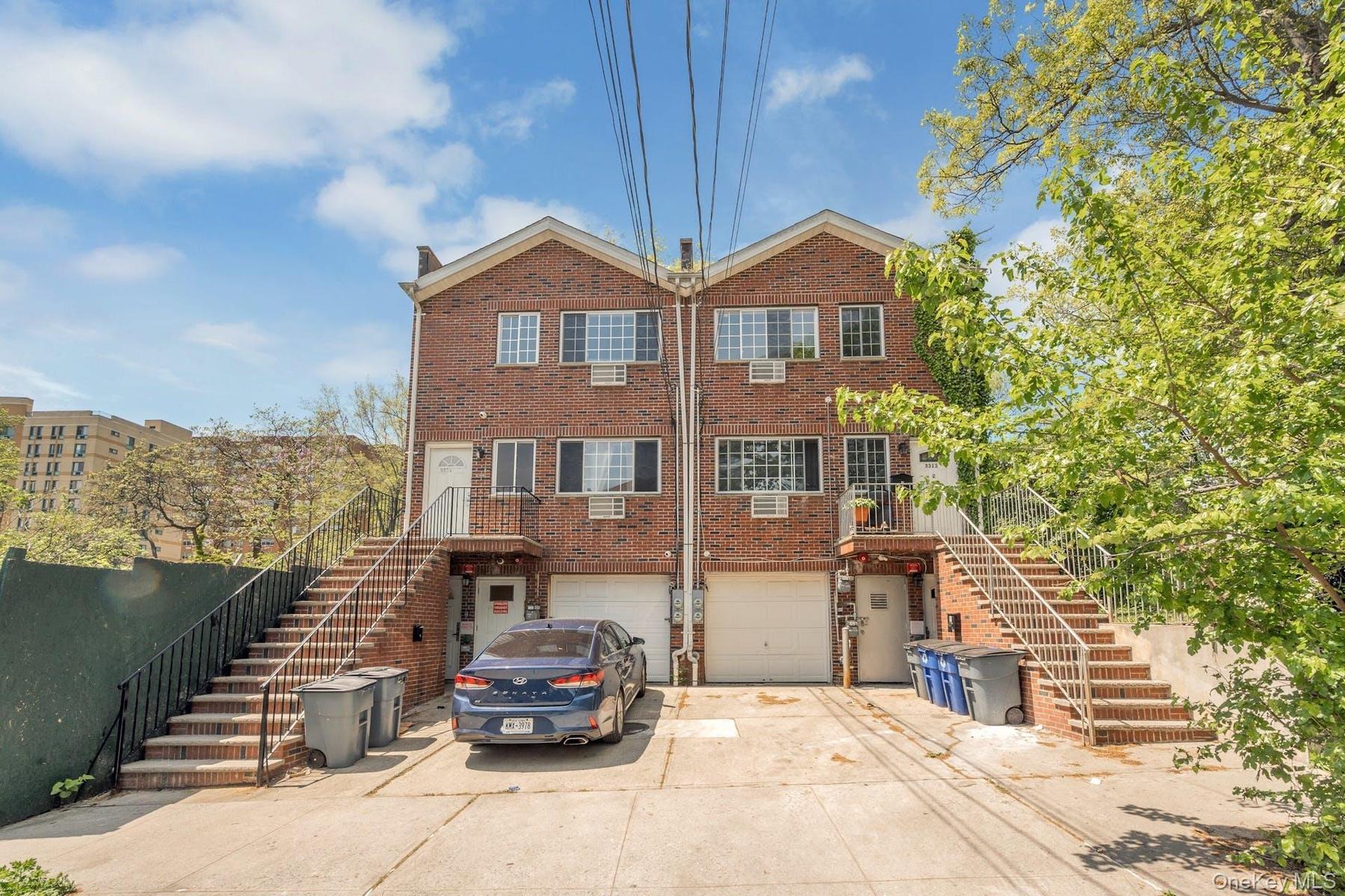 Rear view of house featuring stairway, brick siding, and driveway